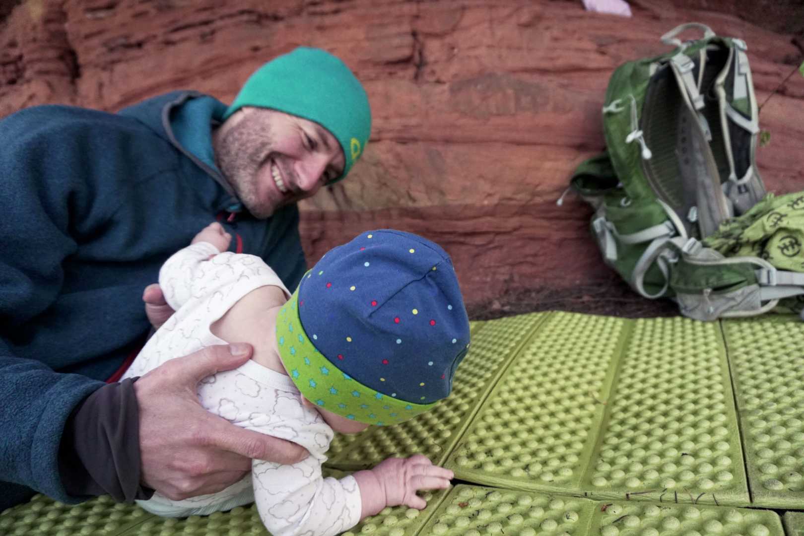 Vater mit Baby auf Isomatte beim Biwakieren